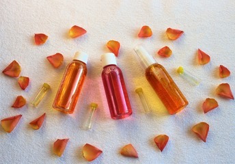 Shower gels in clear bubbles and rose petals on a white towel. Everything for baths and saunas.