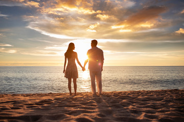 Happy young couple holding hands on beach