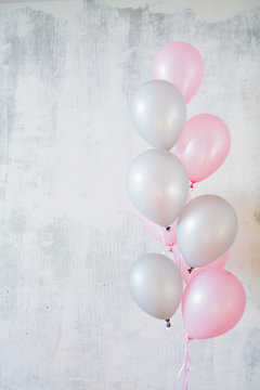 Vertical banner of bunch of pink and gray balloons for birthday party on gray concret background with copy space