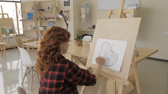 Young pregnant woman drawing painting in art studio, healthy happy lifestyle concept