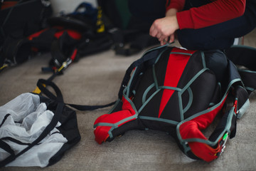 Woman rigger is packing parashute before jumping in the aerodrome room close-up. Face is not...