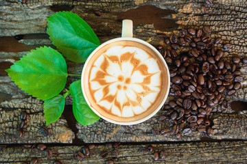 hot cappuccino on wood table /hot cappuccino with coffee bean and green leaf on wood table