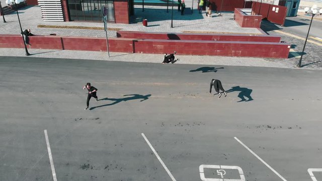 Three athletic young men running on the road and performing tricks. Aerial view