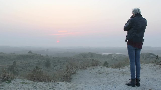 Wide shot of a landscape photographer man taking photos in nature at sunset or sunrise.
