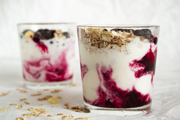 Ice cream with berries and muesli. Ice cream in a glass with currants, berry jam and muesli on a white background. Close-up.