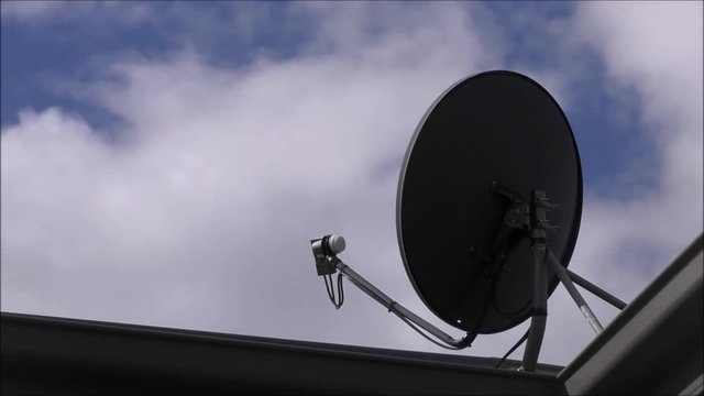 Time lapse of a satellite dish on a rooftop receiving television signals