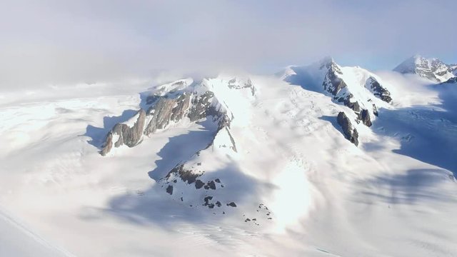Stunning aerial drone footage of two hikers on a mountain ridge (arete) near the summit of Aletschhorn mountain in the Bernese Alps, Switzerland. Ebnefluh and Gletscherhorn mountains in background.