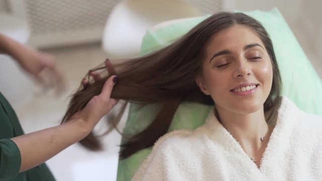 High Angel Shot of Young Caucasian Female Laying on Bed While Her Doctor Taking Care of Her Hair After Mesotherapy Treatment. Light Camera Movement