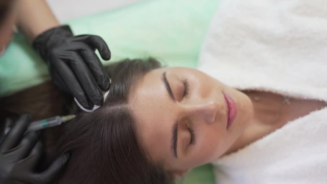 High Angle of Young Caucasian Females Head Under Hair Mesotherapy Treatment and Injection from Doctor With Gloves. Light Camera Movement