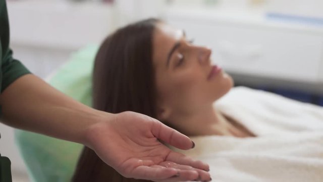 Close Up of Mesotherapy Doctor's Hands Spraying Liquid on Hands for Hair Treatment While Female Patient Laying Down in Background. Light Camera Movement