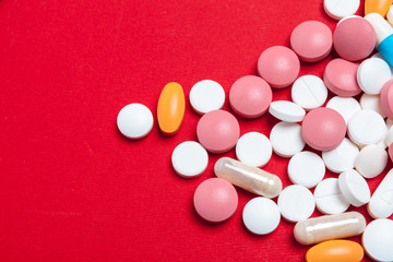 Multicolored pills on red background. Medical concept. Texture.