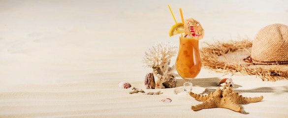 Fototapeta na wymiar panoramic shot of cocktail, starfish, straw hat and sea stones on beach with copy space