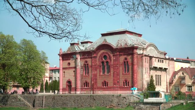 Old building on the waterfront. Clear spring day. In the background there are trees and a beautiful building in the European style on the river embankment.