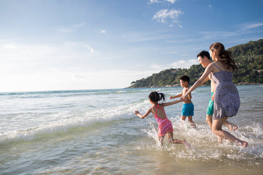 Happy young family running in sea water