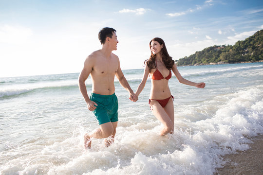 Happy young couple running in sea water