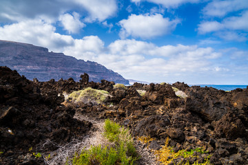 Spain, Lanzarote, Trail though field of solidified lava at north coast with view to huge famara mountains