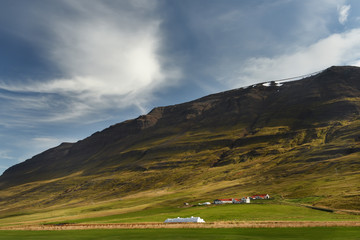 Small houses in the valley among the mountains. Typical Icelandic landscape. A beautiful view of secluded housing.