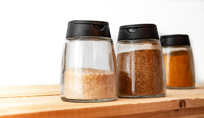 Salt and pepper shakers - Powder spices glass jars on wooden desk 