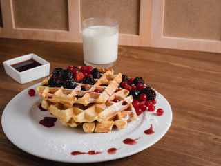 Belgian waffles with berries. milk. Syrup. Wooden table.