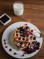 Belgian waffles with berries. milk. Syrup. Wooden table.