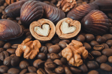  Nuts, chocolate and coffee on a black background. Walnuts in the shape of a heart. Sweets and nuts