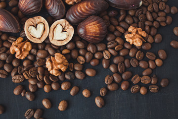  Nuts, chocolate and coffee on a black background. Walnuts in the shape of a heart. Sweets and nuts