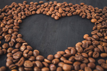  Coffee beans in the form of a heart on a black wooden background. Coffee heart