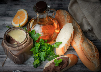 Homemade pasta from offal on the baguette. On the base table there is a glass jar, a lemon, a knife, a baguette, gravy, olive oil and greens. View from above.