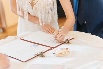 The bride signs on the registration in the document on the wedding day