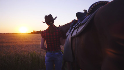 Cowgirl with horse looking at the sunset