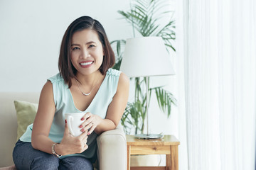 Asian woman sitting on sofa at home