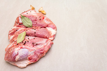 Raw pork shoulder with spices. Bay leaf, garlic. On a stone background, copy space.