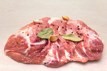 Raw pork shoulder with spices. Bay leaf, garlic. On a stone background, copy space, close up.