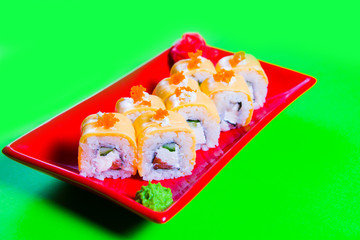A portion of sushi on a red plate. green background