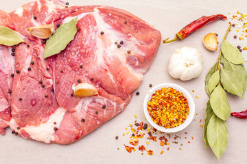 Raw pork shoulder with spices. Bay leaf, garlic. On a stone background, close up, top view.