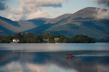 Man canoeing on a lake with hills in background