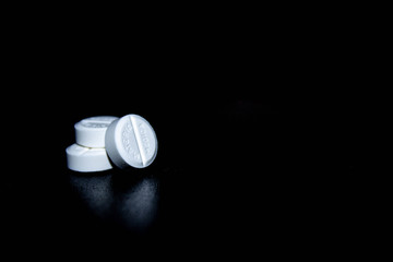 white pills on black glass background. medical pharmacy