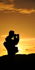 Silhouette of photographer with tripod against setting sun
