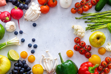 Top view flat lay with various vegetables on concrete background. Enoki mushrooms, asparagus, cherry tomatoes and berries. Summer food ingredients concept