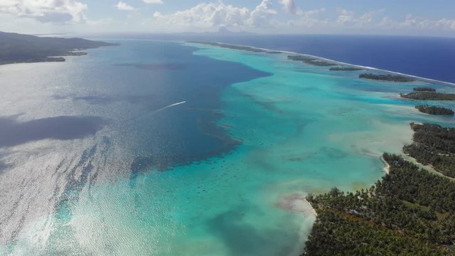 Aerial Lockdown: Tropical Ocean With Different Shades Of Blue Surrounding Islands in Vahine, French Polynesia