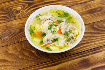 Chicken soup with noodles and vegetables on wooden table
