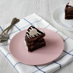 Piece of homemade chocolate cherry cake on a pink plate, side view. Close-up.