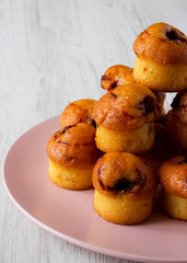Homemade muffins with cherry on a pink plate over white wooden surface, side view. Close-up.