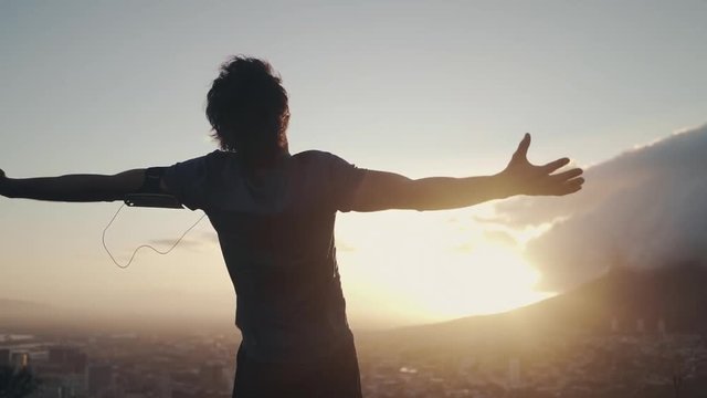 Man with arms wide open on the hill at sunrise