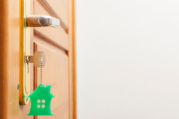 House key on a house shaped silver keyring in the lock of a door