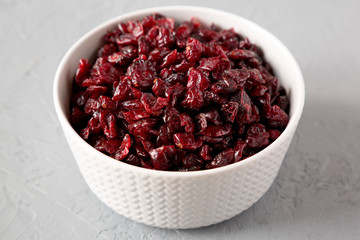 Dried cranberries in a bowl over gray background, side view. Close-up.