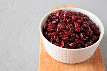 Dried cranberries in a bowl over gray surface, side view. Copy space.