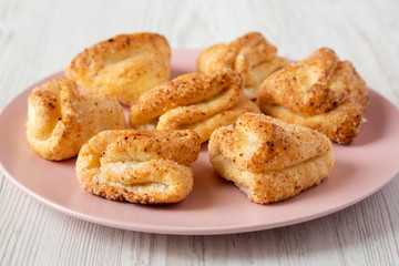 Homemade cottage cheese biscuits on pink plate over white wooden background, low angle view. Close-up.