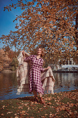 Cute woman with a blanket by the lake in autumn park