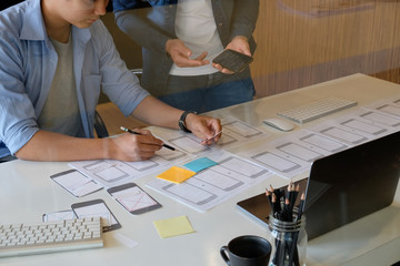 Website designer planning application development draft template layout framework and coding program on paper and computer. © Prathankarnpap